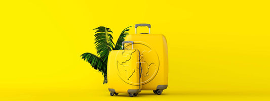 2 gelbe Koffer mit Palmenblatt auf gelben Hintergrund