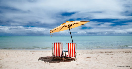 Sandstrand mit Rot Weiß Liegen und gelbem Schirm