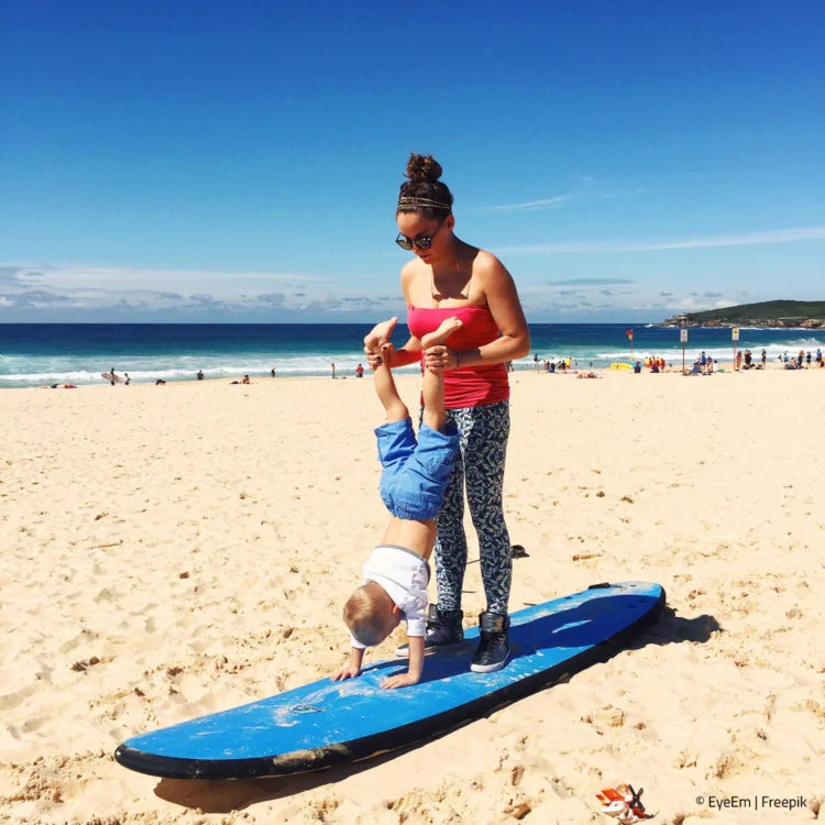 Frau mit Kind am Strand auf Surf-Board