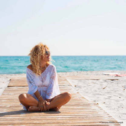 Blonde Frau im Schneidersitz am Meeresstrand