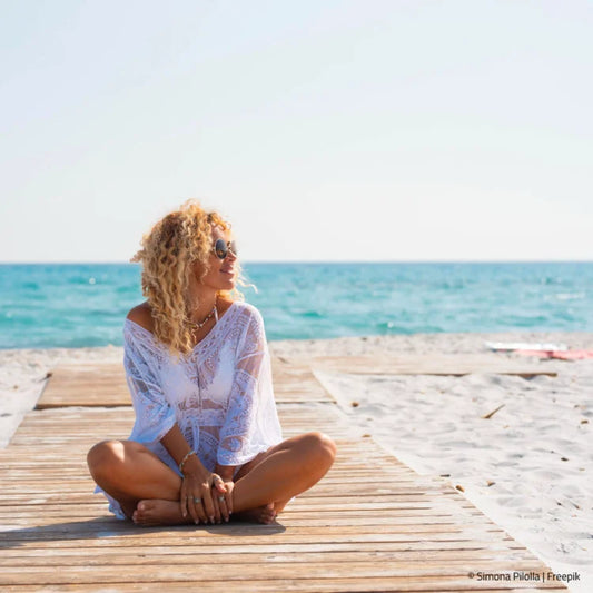 Blonde Frau im Schneidersitz am Meeresstrand