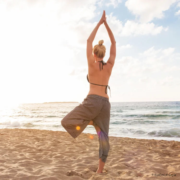 Frau macht Yoga am Sandstrand